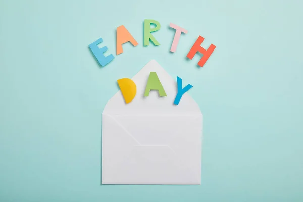 Вид на цветные бумажные буквы и конверт на бирюзовом фоне, концепция Дня Земли — стоковое фото