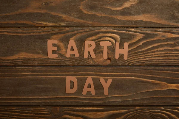 Top view of paper letters on brown wooden background, earth day concept — Stock Photo