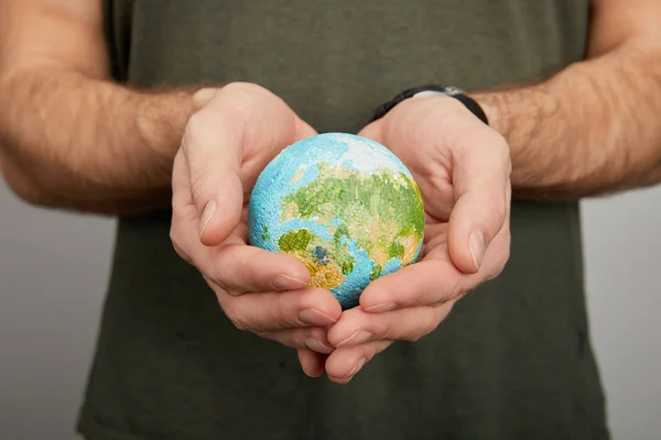 Man holding planet model on grey background, earth day concept — Stock Photo