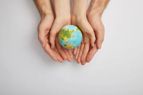 Top view of man and woman holding planet model on grey background, earth day concept — Stock Photo