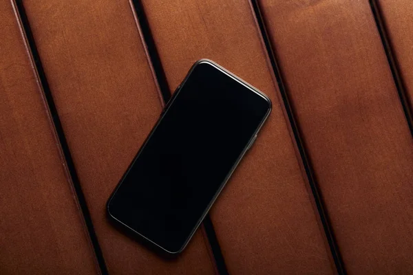 Vista superior del teléfono inteligente con pantalla en blanco y espacio de copia en la mesa de madera - foto de stock