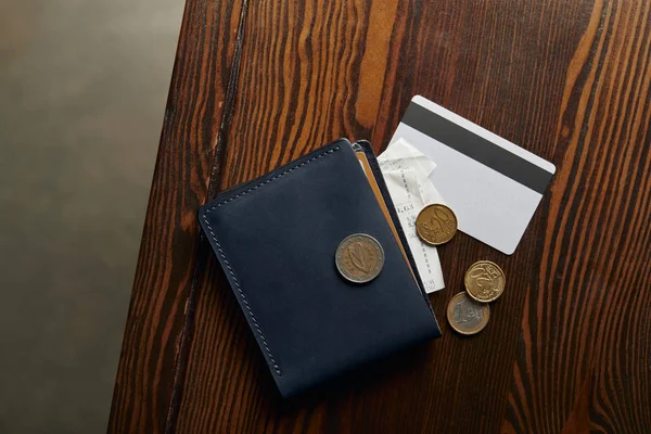 Top view of wallet with credit card, coins and cheque on wooden table — Stock Photo