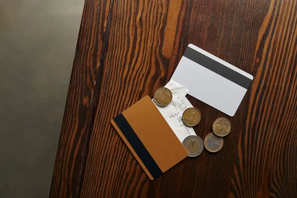 Вид сверху на кредитные карты, монеты, чек на деревянный стол — стоковое фото