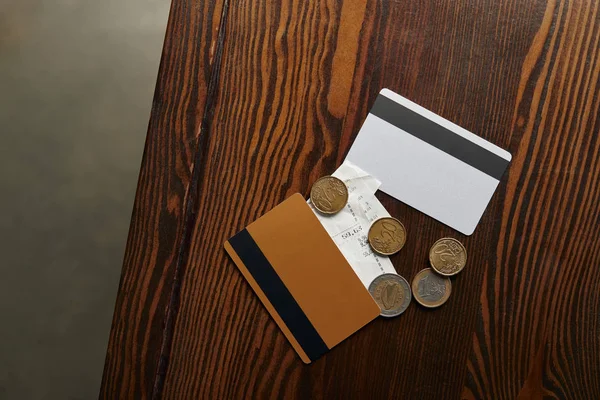 Top view of credit cards, coins, cheque on wooden table — Stock Photo