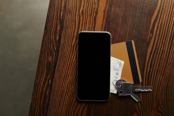 Vue du haut de la carte de crédit, smartphone, chèque et clés sur table en bois — Photo de stock