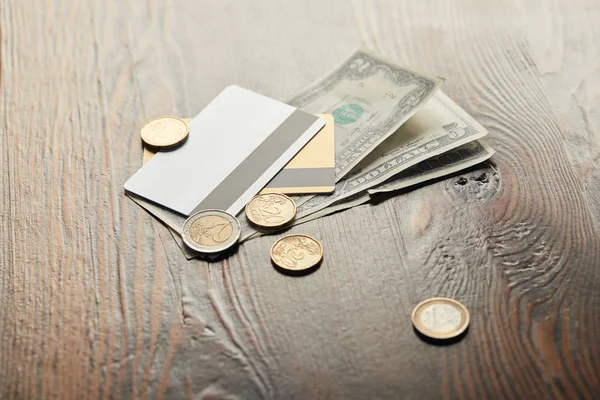 Billetes, monedas y tarjetas de crédito en dólares sobre mesa de madera - foto de stock