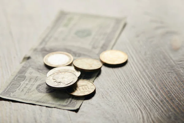 Foco seletivo de notas de dólar e moedas em mesa de madeira — Fotografia de Stock