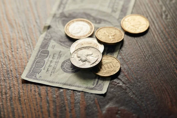 Enfoque selectivo de billetes y monedas en dólares en la superficie de madera - foto de stock