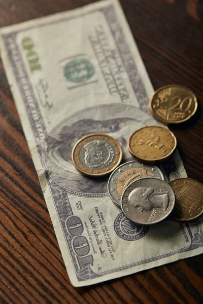 Messa a fuoco selettiva delle banconote e delle monete in dollari sul tavolo di legno — Stock Photo