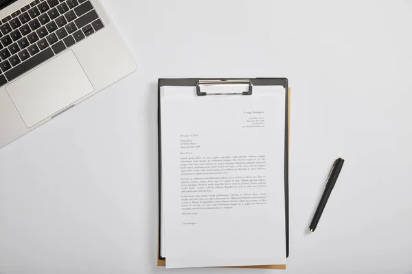 Верхний вид документации в буфер обмена, ручка, ноутбук на столе — стоковое фото