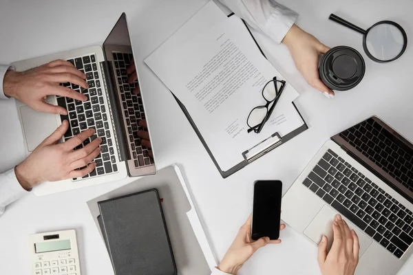 Vista superior de empresários digitando em laptops, segurando smartphone e copo de papel — Fotografia de Stock