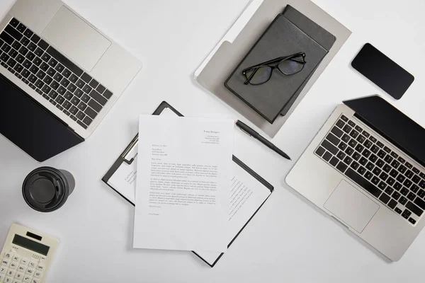 Верхний вид документации в буфер обмена, бумажная чашка, ноутбуки, смартфон, ноутбуки, папка, калькулятор и очки — стоковое фото