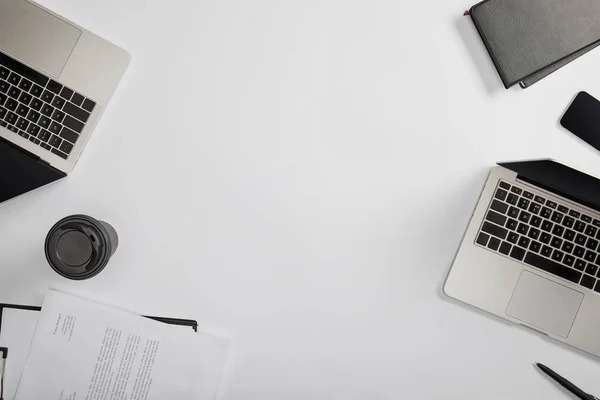 Top view of documet on clipboard, paper cup, laptops, pen, notebooks — Stock Photo