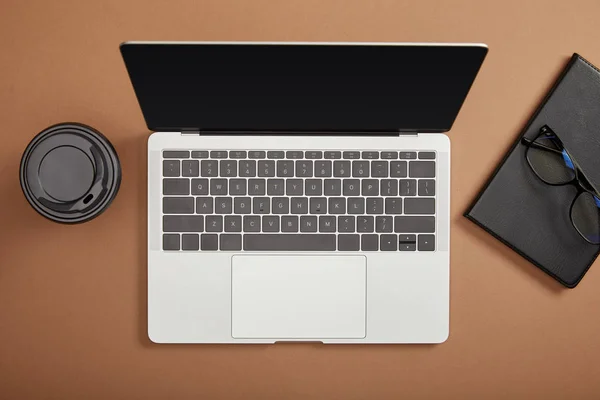 Vista superior do laptop, copo de papel, óculos e notebook — Fotografia de Stock
