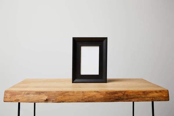 Black square frame on wooden table at home — Stock Photo