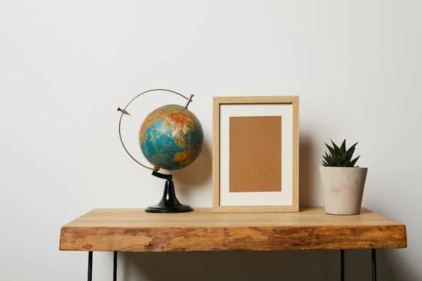 Globo cerca de marco y planta en maceta en mesa de madera - foto de stock