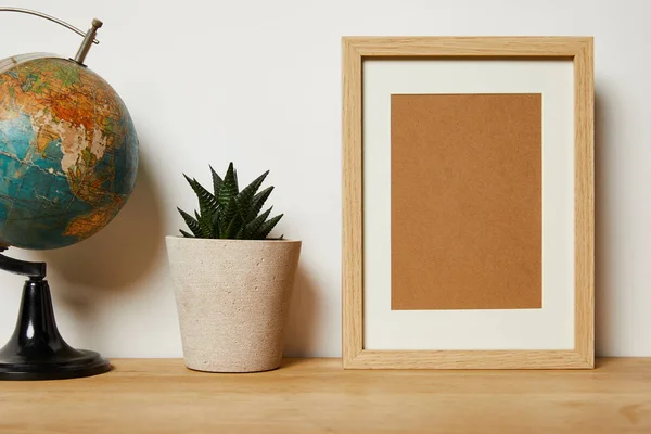 Blank frame near globe and green plant in pot — Stock Photo