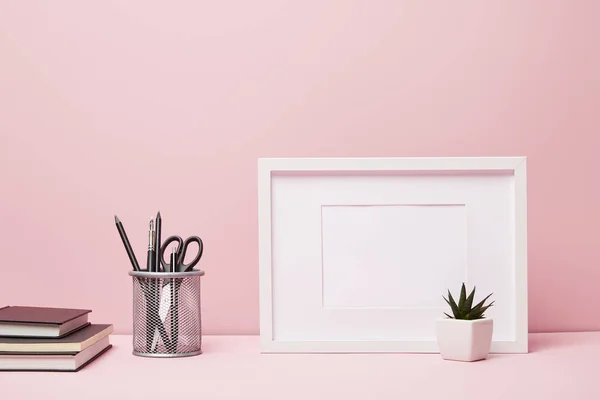 Blank frame near green cactus, metallic holder with stationery and books — Stock Photo
