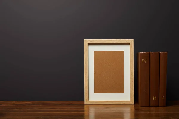 Quadro de madeira em branco perto de livros na tabela texturizada — Fotografia de Stock