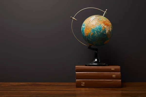 Globe near books on wooden textured table — Stock Photo