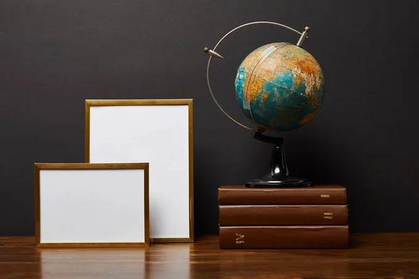 Globe on books near blank frames on table — Stock Photo