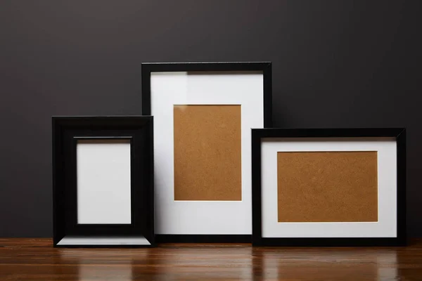 Black blank square frames on wooden table — Stock Photo