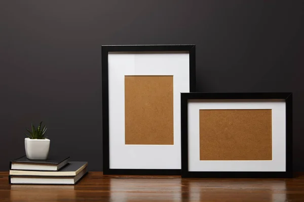 Marcos cuadrados negros cerca de libros y plantas en mesa de madera - foto de stock