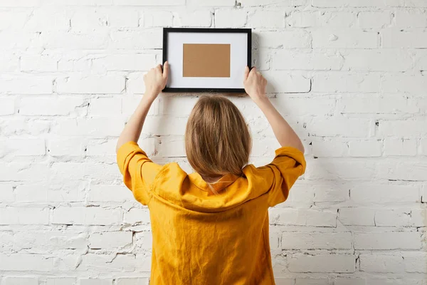 Back view of woman holding blank black frame in hands — Stock Photo