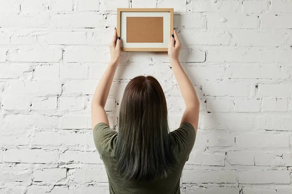 Vista posteriore della donna che tiene vuoto cornice marrone in mano — Foto stock