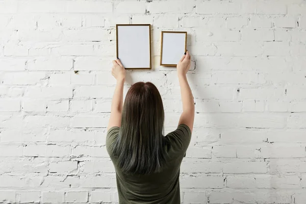 Vista trasera de la mujer sosteniendo el marco cuadrado en blanco en las manos - foto de stock