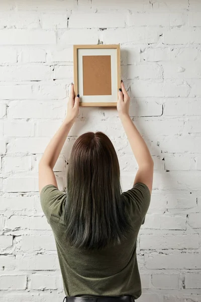 Back view of woman holding blank brown square frame in hands — Stock Photo