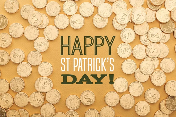 Top view of golden shiny coins near happy st patricks day lettering on orange background — Stock Photo