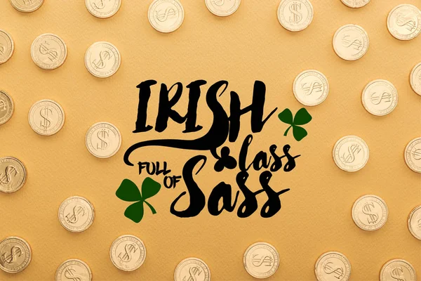 Draufsicht auf glänzende Münzen mit Dollarzeichen in der Nähe des irischen Lasses voller Sass-Schriftzüge auf orangefarbenem Hintergrund — Stockfoto