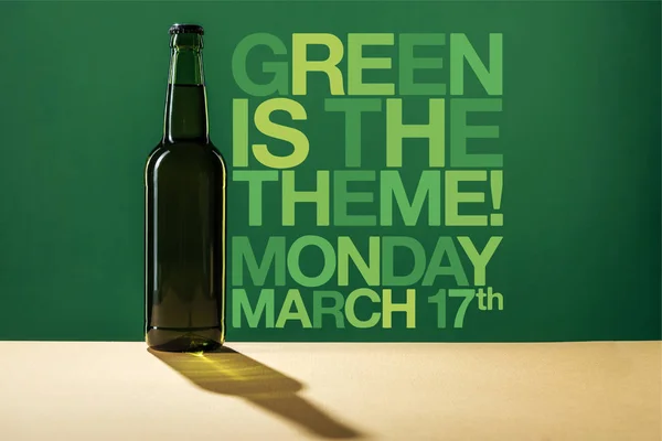 Botella de cerveza de vidrio cerca de verde es el tema de letras sobre fondo verde - foto de stock