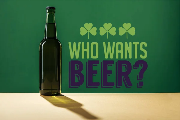 Стеклянная бутылка пива рядом кто хочет пивные буквы на зеленом фоне — стоковое фото