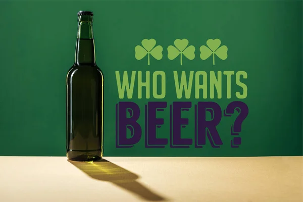 Glass beer bottle near who wants beer lettering on green background — Stock Photo