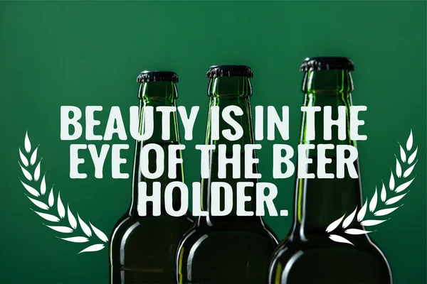Beer bottles near beauty is in the eye of the beer holder lettering on green background — Stock Photo