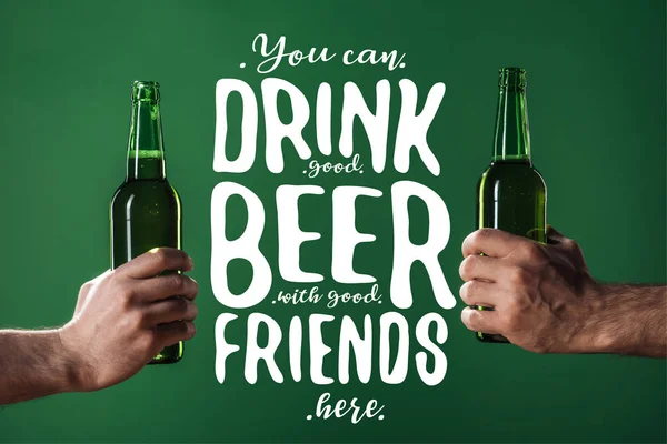 Cropped view of men holding beer bottles near you can drink good beer with good friends here lettering on green background — Stock Photo