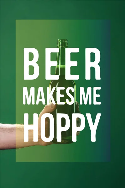 Cropped view of man holding beer bottle near beer makes me hoppy lettering on green background — Stock Photo