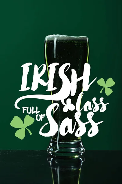 Glass of beer with foam near irish lass full of sass lettering on green background — Stock Photo