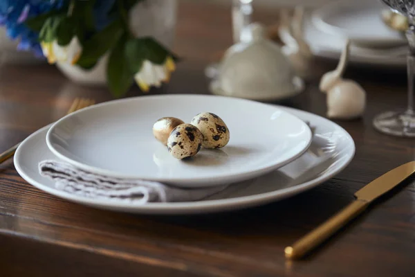 Enfoque selectivo de huevos de codorniz en platos blancos y mesa de madera en casa - foto de stock