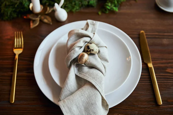Fuoco selettivo di uova di quaglia su tovagliolo e piatti vicino a muschio verde e posate su tavolo di legno — Foto stock