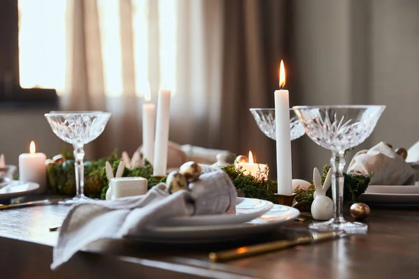 Selektiver Fokus brennender Kerzen in der Nähe von Tellern und Kristallgläsern auf dem heimischen Holztisch — Stockfoto