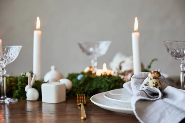 Selektiver Fokus von Wachteleiern auf Servietten und Tellern in der Nähe von grünem Moos, Kerzen und Kristallgläsern auf dem heimischen Holztisch — Stockfoto