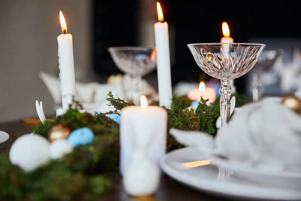 Selective focus of burning candles, green moss and crystal glasses on wooden table at home — Stock Photo