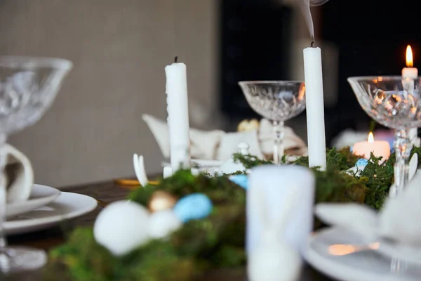 Selective focus of candles, green moss and crystal glasses on wooden table at home — Stock Photo