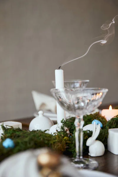 Focus selettivo di candele, vetro cristallo e coniglietti decorativi su tavolo in legno a casa — Foto stock