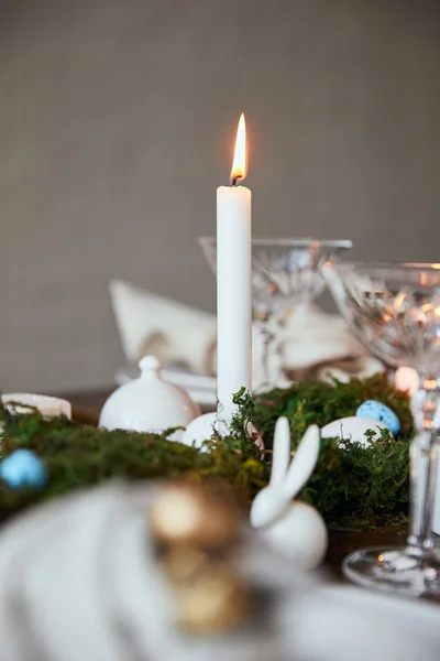 Foco seletivo de velas em chamas, óculos de cristal e coelho decorativo na mesa de madeira em casa — Fotografia de Stock