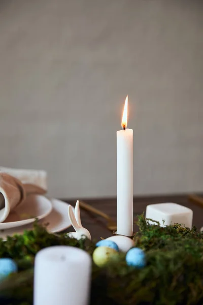 Selective focus of burning candle and plates near moss on wooden table at home — Stock Photo