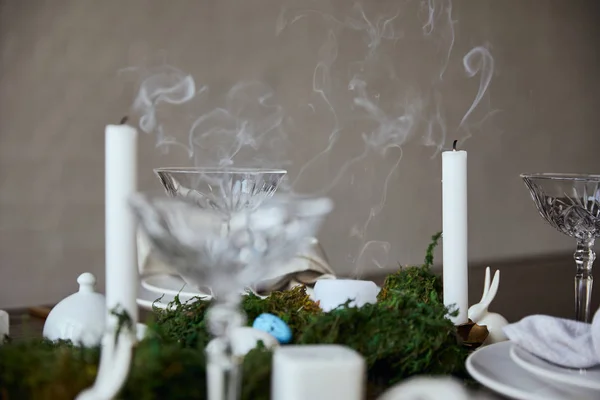 Fuoco selettivo di candele vicino a bicchieri di cristallo e muschio sul tavolo di legno a casa — Foto stock